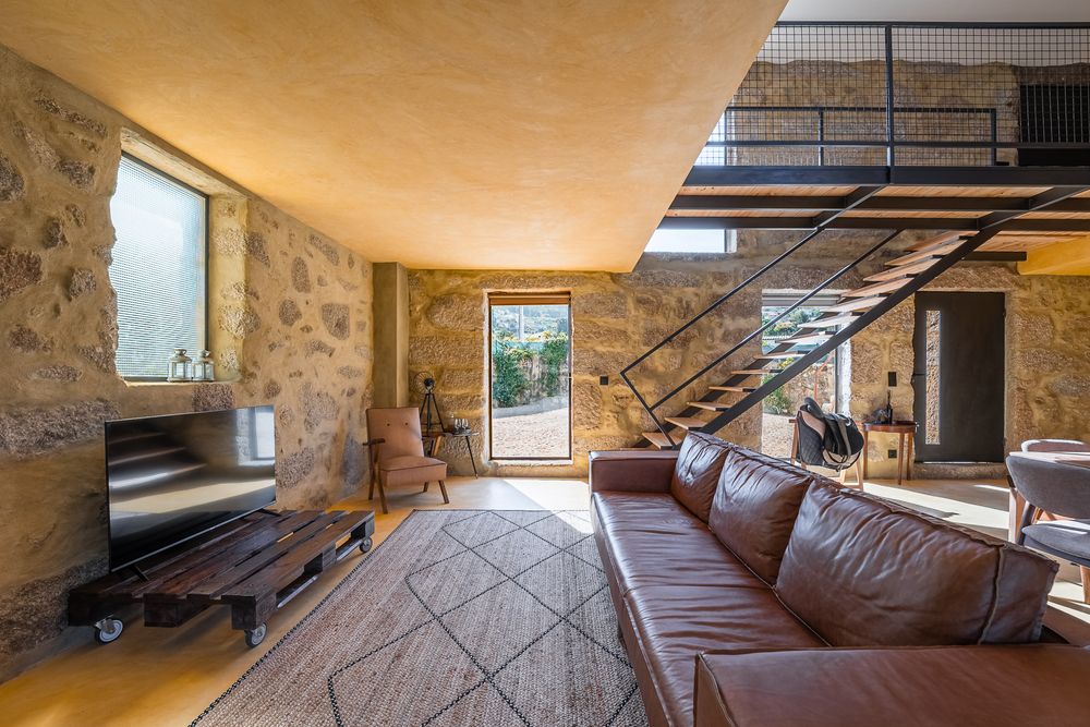Sala da Lemon Villa com paredes de pedra e escada de ferro