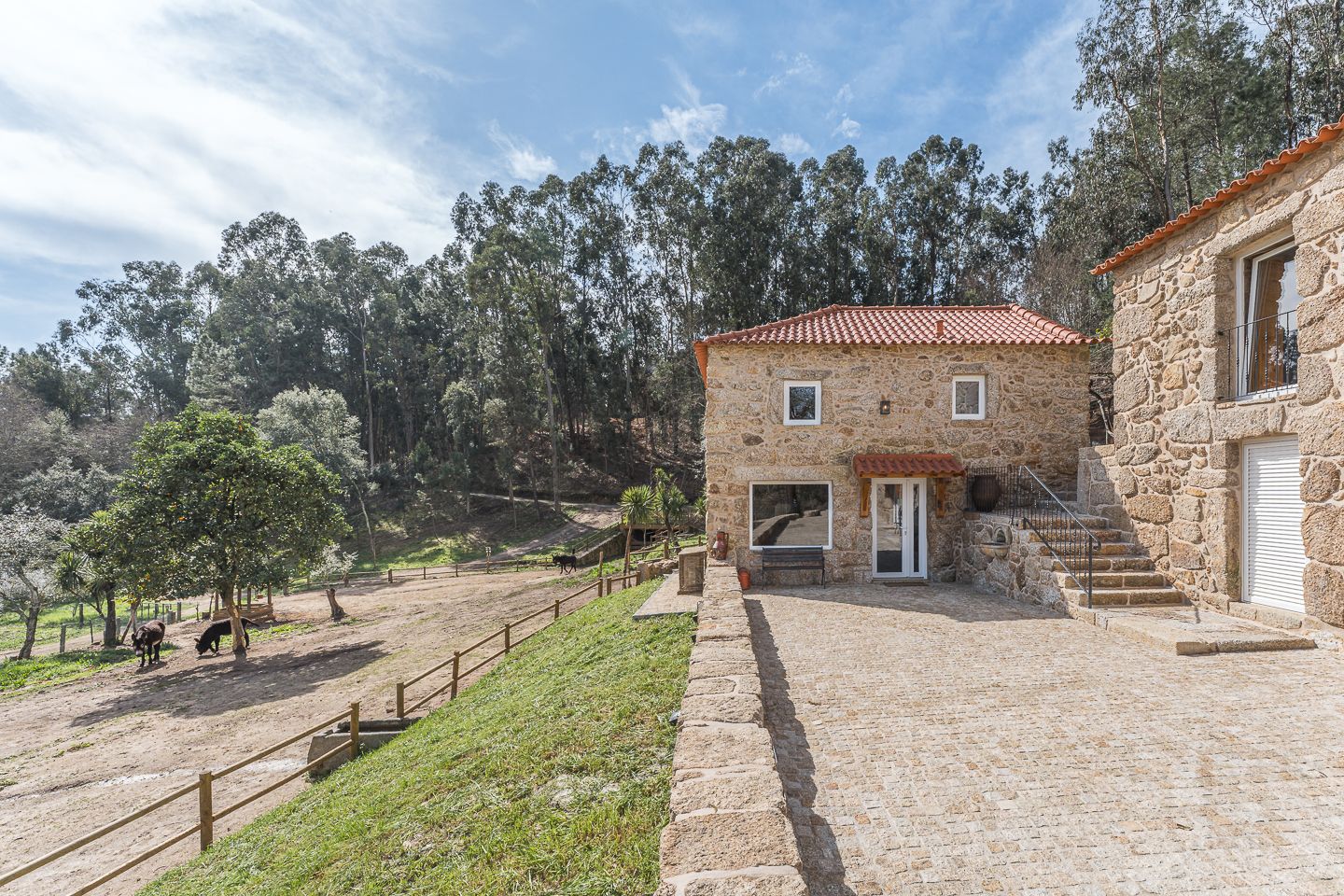 Casa do Burro em pedra, com os burros no cercado ao lado