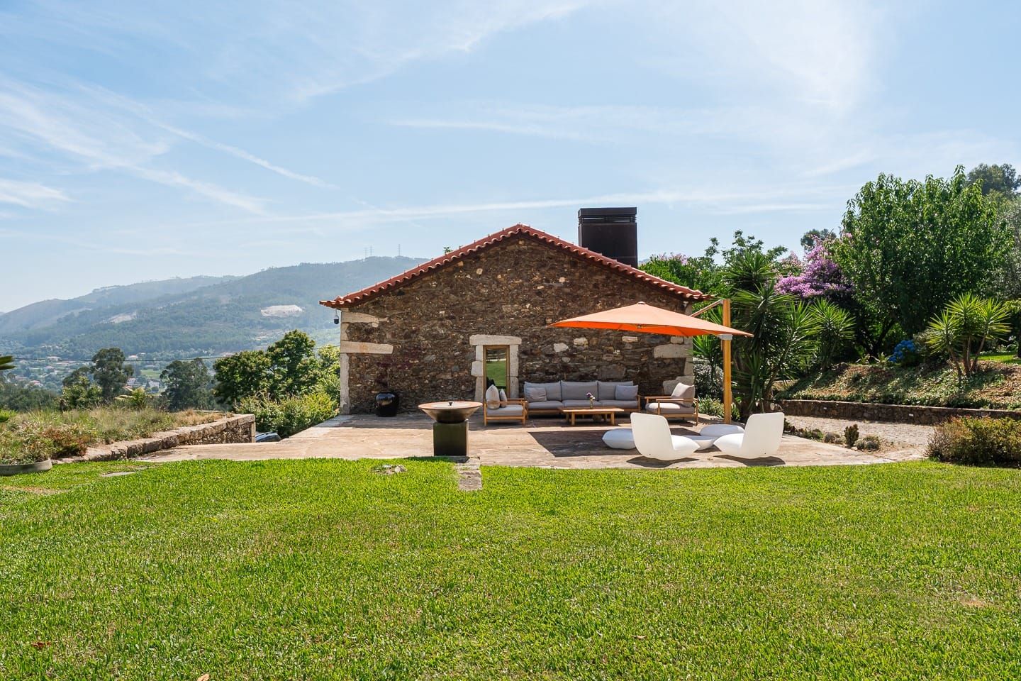 Casa da Eira, em pedra, com o terraço, o relvado e o vale ao fundo