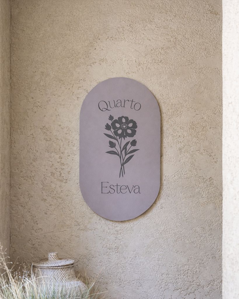 Placa lilás do Quarto Esteva numa parede clara